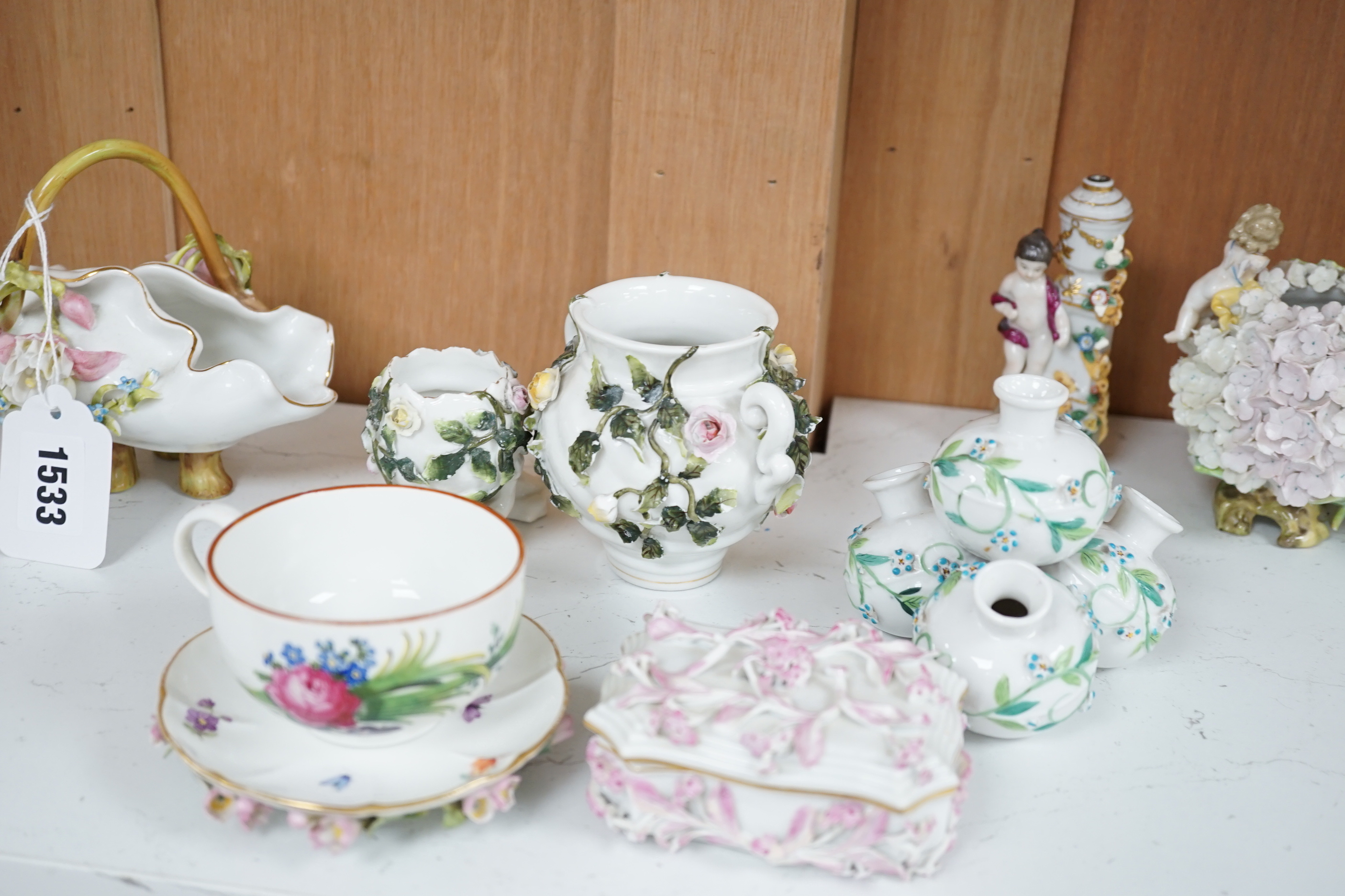 A group of German flower encrusted tableware, including a matched Meissen cup and saucer, lidded box, salts, figures, etc., tallest figure 12cm